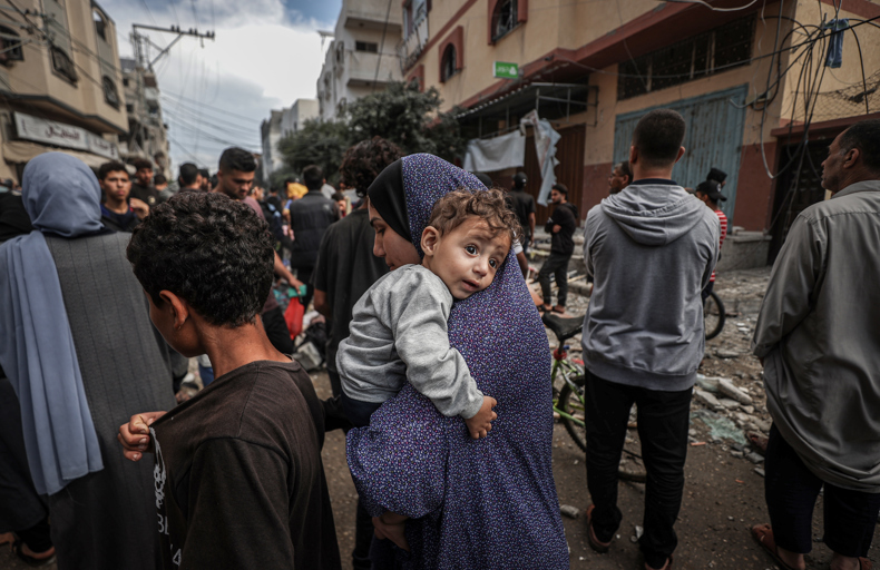 A mother carrying her child amidst a crowd